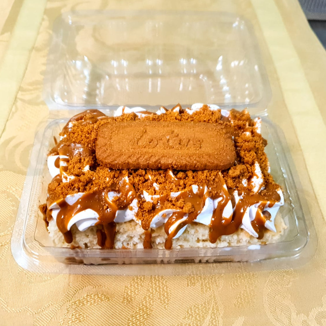 Biscuit dessert in a transparent plastic container on a textured surface